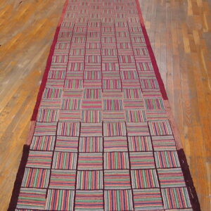 Multicolor checkerboard runner with red, green, and blue stripes on light plank wood flooring.