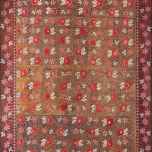 Textured brown and rust rug featuring red and pink floral motifs with grey leaves and elaborate decorative borders.