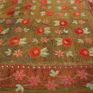 High-pile rug featuring red and pink floral motifs on an earthy brown and gold textured field.