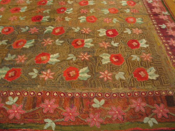 High-pile rug featuring red and pink floral motifs on an earthy brown and gold textured field.