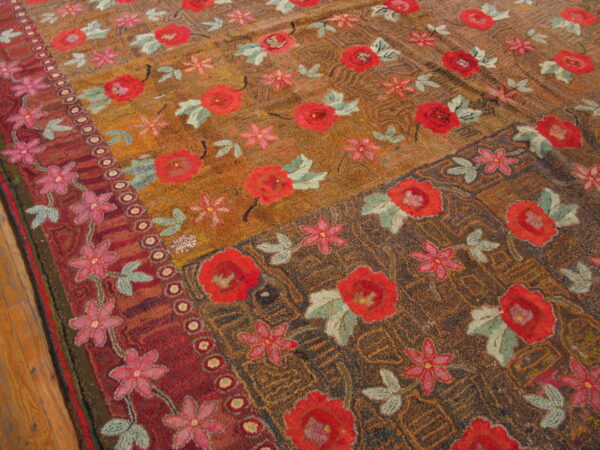 Textured floral rug with red and pink blossoms on brown and gold fields, shown near wood flooring.