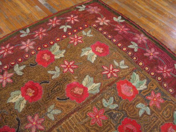 Brown and rust floral rug with red roses and pink flowers lying on a hardwood floor.
