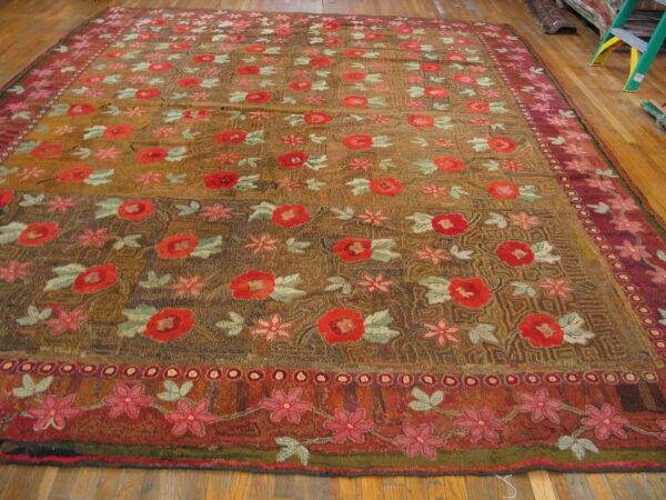 Large, textured pile rug with red floral motifs and burgundy borders on hardwood flooring.