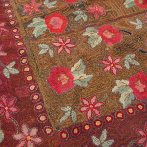 Textured loop pile rug with large pink flowers, blue leaves, and a dotted maroon border.