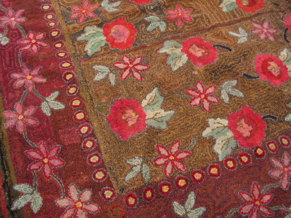 Textured loop pile rug with large pink flowers, blue leaves, and a dotted maroon border.
