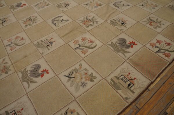 Cream and tan hooked rug displaying houses, roosters, and floral motifs in a diamond grid on wood floor.