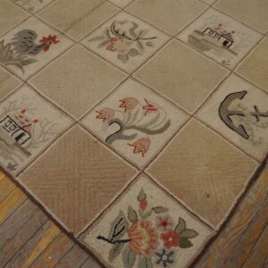 Beige hooked rug with pictorial blocks, including flowers and an anchor, on rustic distressed wood flooring.