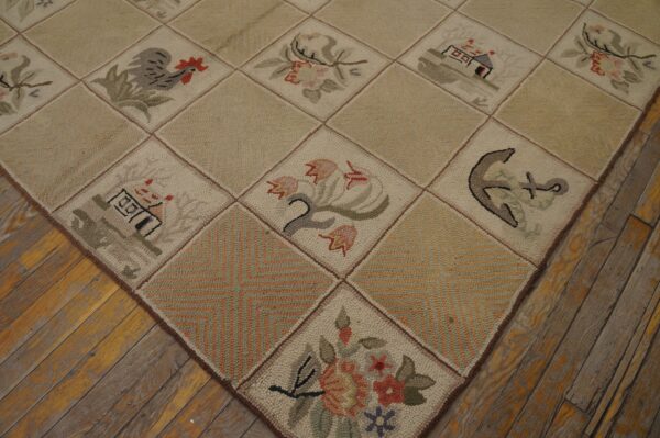 Beige hooked rug with pictorial blocks, including flowers and an anchor, on rustic distressed wood flooring.