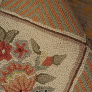 Textured rug featuring cream floral and green/orange geometric patterns, displayed on distressed yellow wooden flooring.