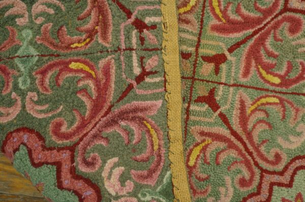 Textured green rug with red and pink scrollwork motifs, separated by a visible vertical burlap seam.