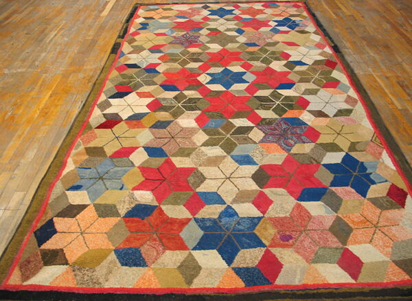Low-pile rug with a complex red, blue, green, and beige geometric star pattern on wood floor.