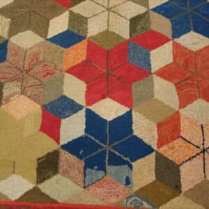 Multicolored rug with a textured pile, displaying a geometric tumbling block pattern in red, blue, and earth tones.