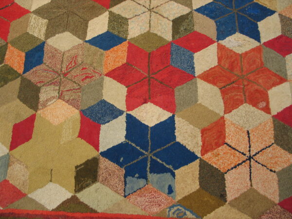 Multicolored rug with a textured pile, displaying a geometric tumbling block pattern in red, blue, and earth tones.