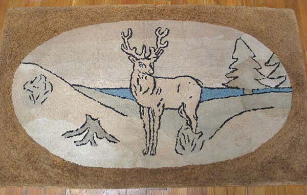 Rustic tan rug with a central cream oval depicting a deer, pine trees, and a blue stripe on wood floor.