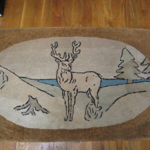 A textured beige rug with a brown border displays a deer and pine tree scene on wood flooring.