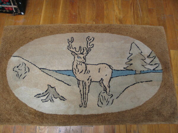 A textured beige rug with a brown border displays a deer and pine tree scene on wood flooring.