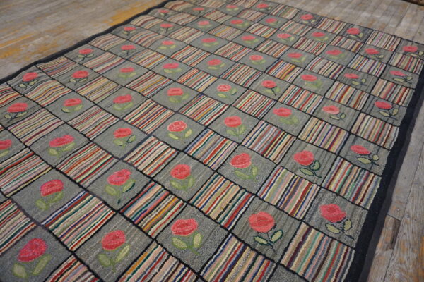 Gray and multicolored checkered rug with pink rose motifs displayed on rustic wood flooring.
