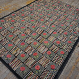 Gray and multicolored checkered rug with pink rose motifs rests on rustic wood planks.