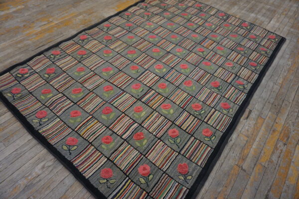 Gray and multicolored checkered rug with pink rose motifs rests on rustic wood planks.