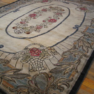 Beige and muted blue floral rug featuring a central rose garland oval on wooden plank flooring.