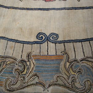 Close-up showing a cream rug with navy lines, scrolls, and multicolored botanical scrollwork at the bottom.