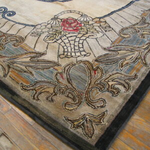 A textured rug corner featuring a beige field, red rose, and scrolling brown/blue motifs rests on wood floors.