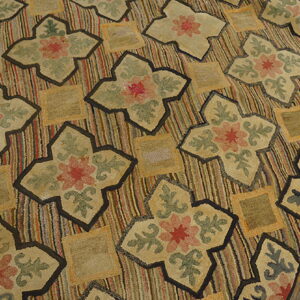 Low-pile rug with colorful vertical stripes and dark-outlined floral medallions on distressed wood floorboards.