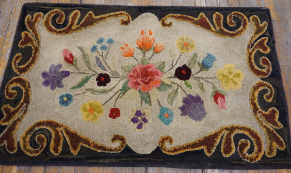 Textured rug with a colorful floral bouquet and dark scrolled border, lying on weathered wood planks.