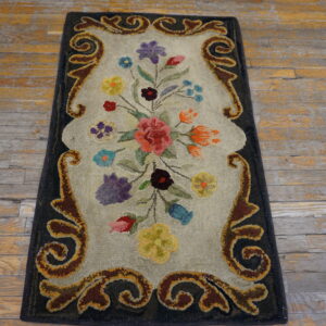 Hooked runner featuring a multicolored floral bouquet and brown scrolled border on rustic wood flooring.