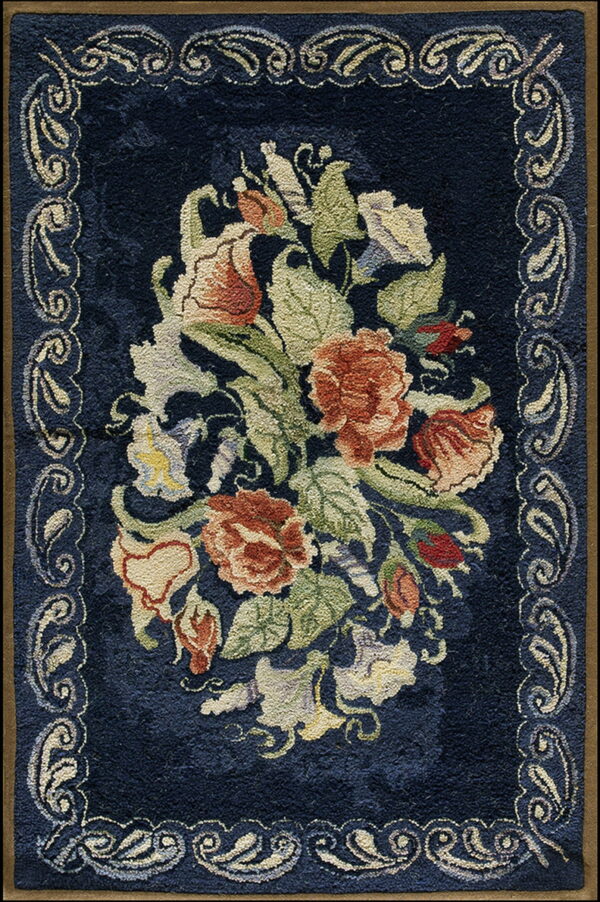 Textured navy blue rug displaying a floral medallion of rust, cream, and green, framed by a scrolled light border.