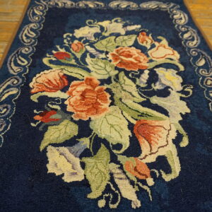 Dark blue high-pile runner with a large center motif of coral and green florals on a wooden floor.