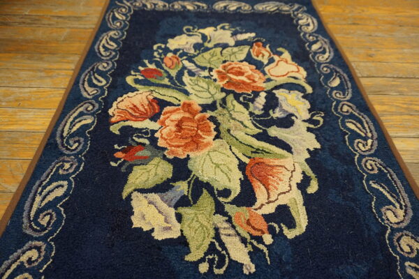 Dark blue high-pile runner with a large center motif of coral and green florals on a wooden floor.