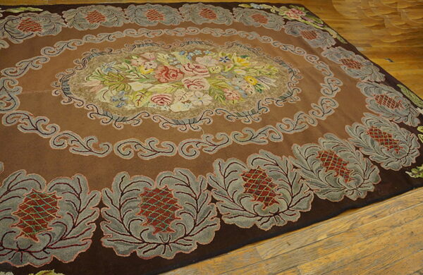 Plush brown rug featuring an elaborate multicolored floral center and gray botanical border on wood.