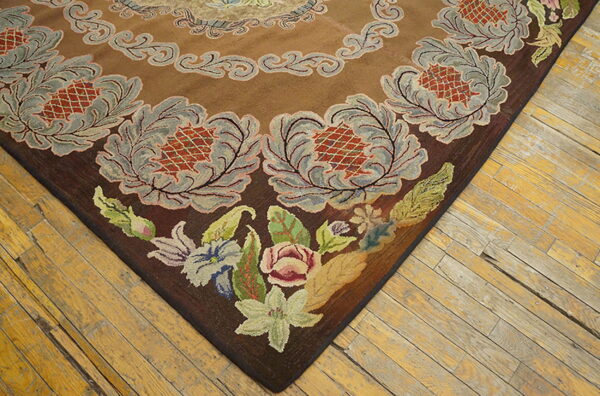 Textured brown rug corner with gray ornate motifs and colorful low-pile flowers, set on distressed wood flooring.