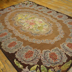 Brown high-pile rug with a multicolored floral medallion and stylized gray borders, set on wood flooring.