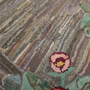Textured rug detail showing gray and earthy diagonal stripes interspersed with vivid pink and orange flowers.