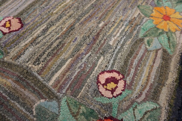 Textured rug detail showing gray and earthy diagonal stripes interspersed with vivid pink and orange flowers.