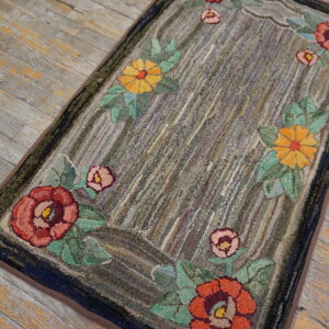 Textured rug featuring a colorful floral border against a mottled gray striped center on rustic wood planks.