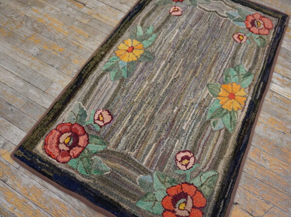 Textured rug featuring a colorful floral border against a mottled gray striped center on rustic wood planks.