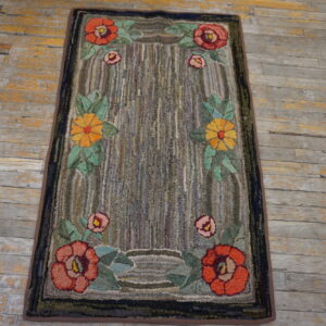 Red and yellow floral rug with a chunky striped gray field resting on distressed plank flooring.