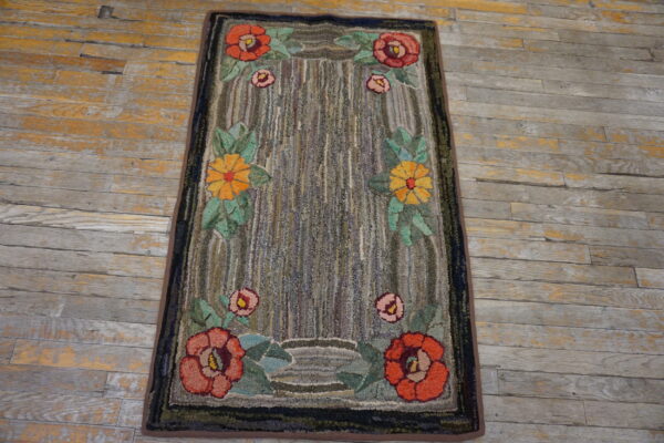 Red and yellow floral rug with a chunky striped gray field resting on distressed plank flooring.