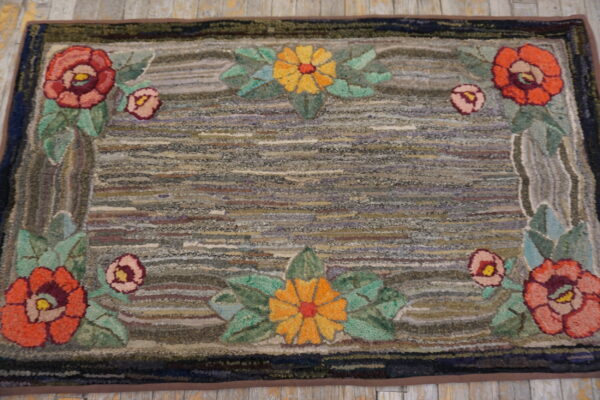 Floral-bordered rug with a textured, multicolored striped field resting on rustic wooden flooring.