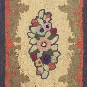 Textured hooked rug displaying a central multi-color floral motif on yellow, bordered by coral and dark blue.