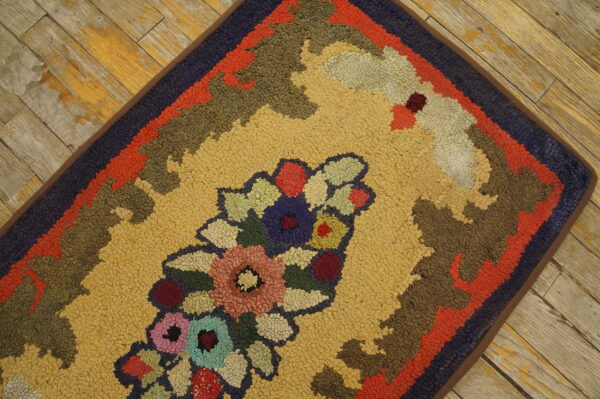 Looped pile rug featuring a multicolored floral medallion on a gold field, placed on distressed wood flooring.