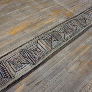 Textured runner featuring multicolored concentric diamond patterns rests on distressed gray wooden floorboards.