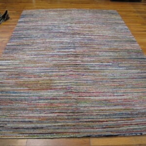 Textured multicolor striped rug featuring horizontal bands of blue, red, cream, and gray on wood planks.