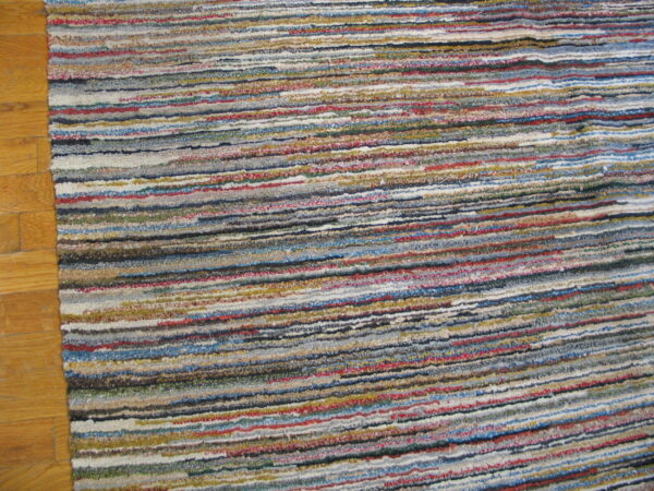 Multicolor horizontally striped rug with visible texture covering light brown wood flooring.