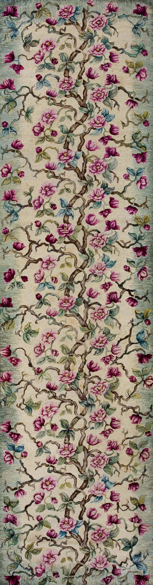 Narrow runner rug with pink flowers and brown branches on a cream field and sage green border.