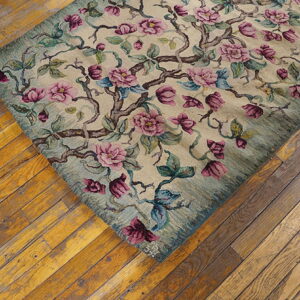 Beige rug featuring pink, magenta, and teal floral branches lying diagonally on rustic hardwood floors.
