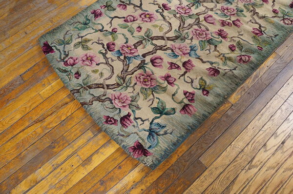 Beige rug featuring pink, magenta, and teal floral branches lying diagonally on rustic hardwood floors.